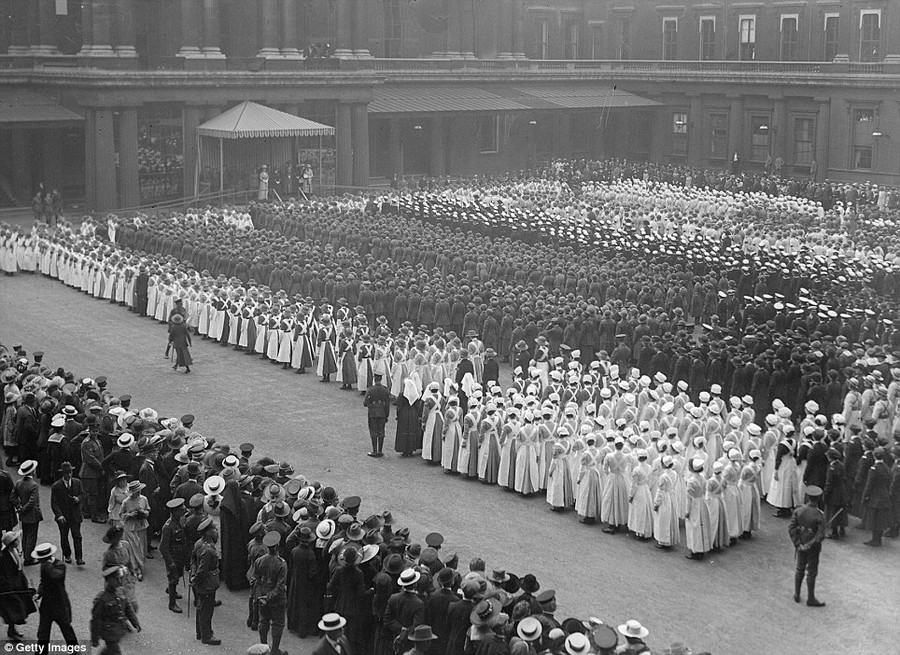 Impressive: Women war workers, including the distinctively white-capped and aproned VAD nurses, parade outside Buckingham Palace in 1918