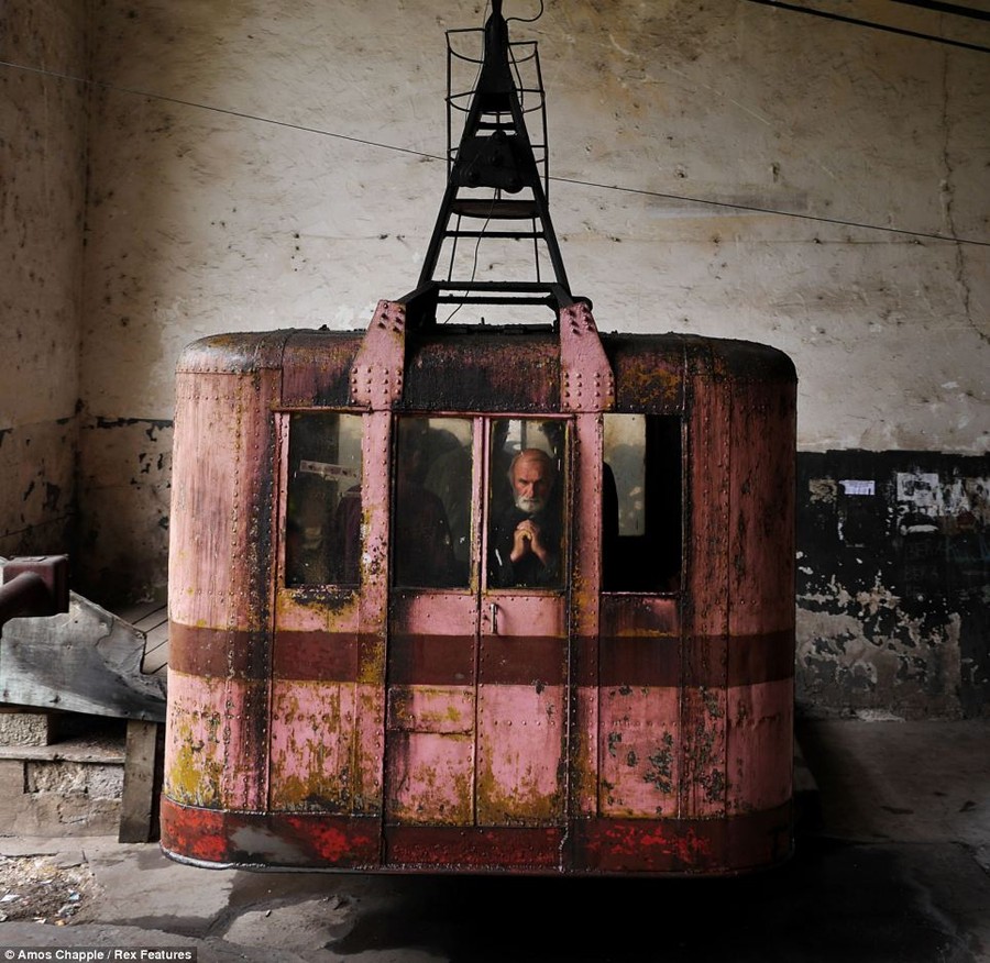 Fear: A man appears to be praying as he boards the rust-ridden cable car on the journey down to the bottom of the valley