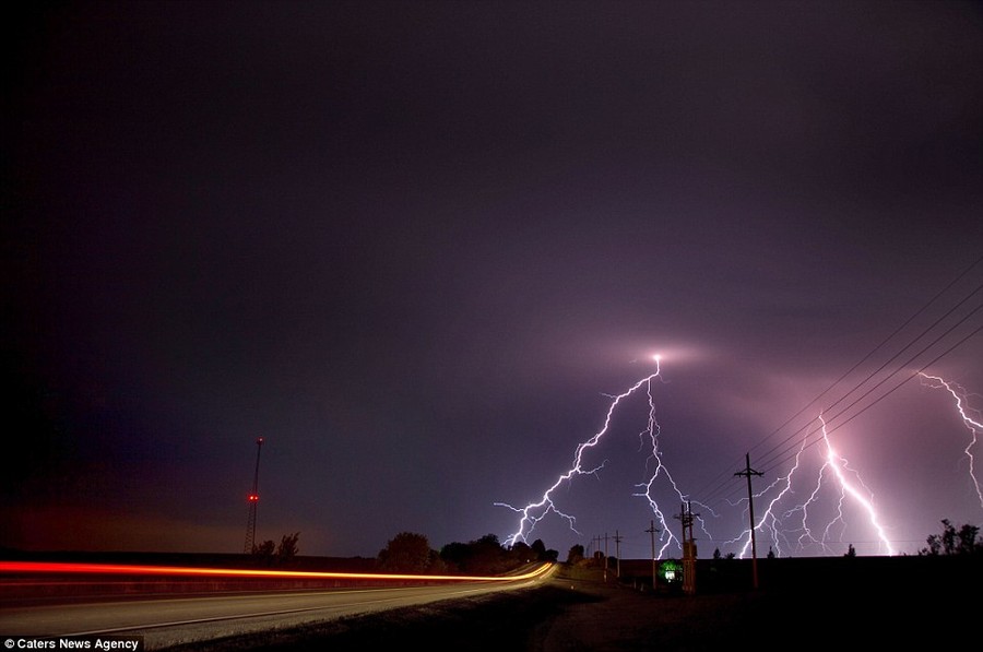 The long trail of a car's rear lights shows the length of exposure used to create this incredible image of lightning striking the ground