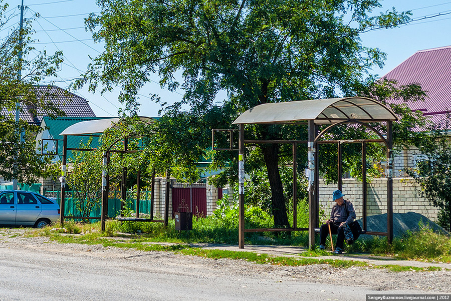 16. Та же остановка. Через дорогу ситуация повторяется. Даже эти металлические каркасы были установлены прямо на разбитом асфальте в траву. Снова стоит обратить внимание на песчаные наносы, за которыми не видно даже бордюра.