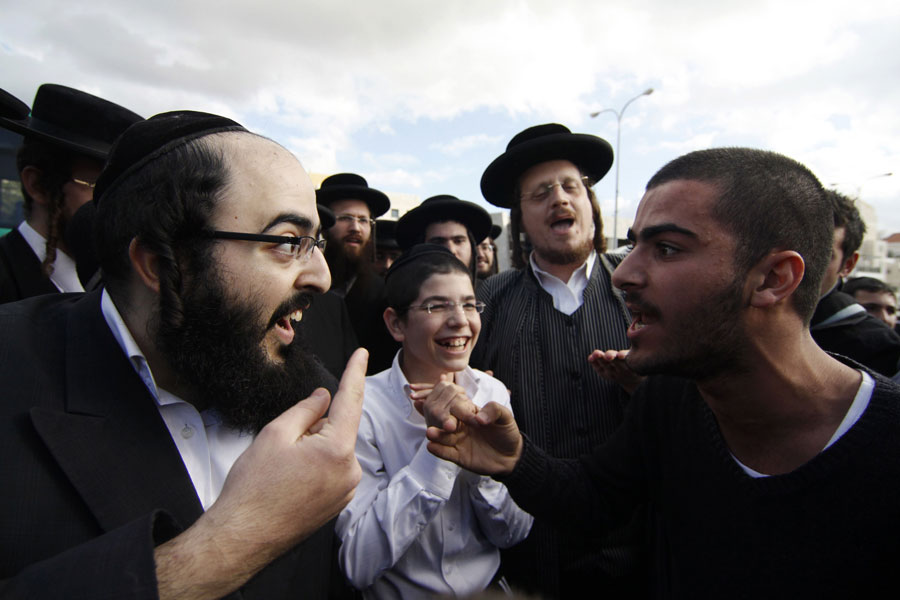 Ортодоксальный еврей спорит со светским израильтянином во время проведения акции протеста. © Reuters