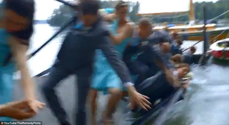 Oops! The wedding party is seen plunging into the water as the dock gives way after a bolt popped out 